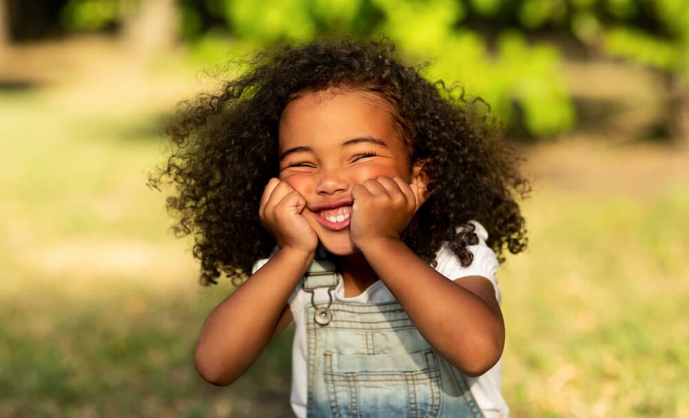 An adorable little girl with long hair has a beautiful hairstyle without any hair accessories or thick braids.