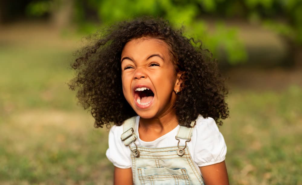 A little girl with beautiful bouncy curls after her mother removed a braided hairstyle with cute pink beads.