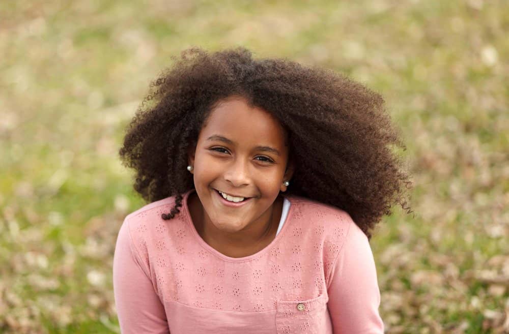 A cute young 12-year-old female with naturally wavy hair wearing casual clothes on a cool autumn day.