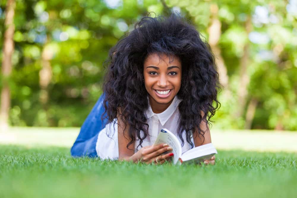 A young student is reading a book about the history of hairstyles for black kids and teenage girls over the years.