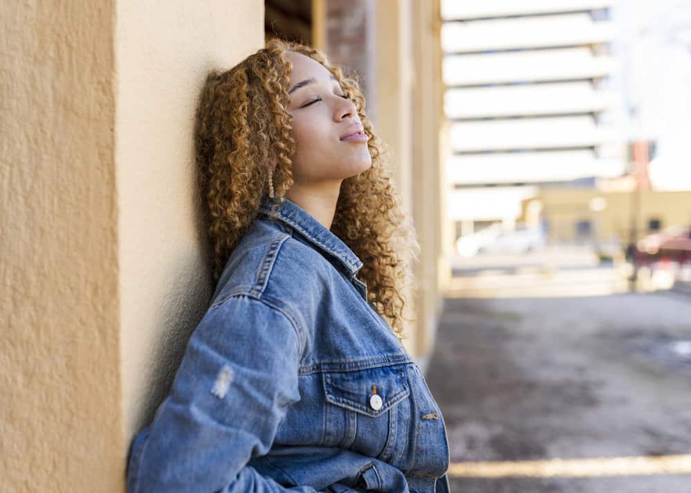 A pretty black girl posing for a photo where she shows off a cute birthday style wearing an old-school blue jean jacket.
