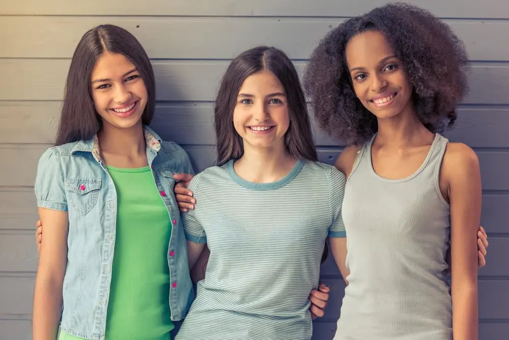 Popular 80s Teenager Hairstyles for Black and White Girls 8 Two white girls with flawless perms and a black girl wearing a curly hairstyle with blunt bangs with sharp layers.