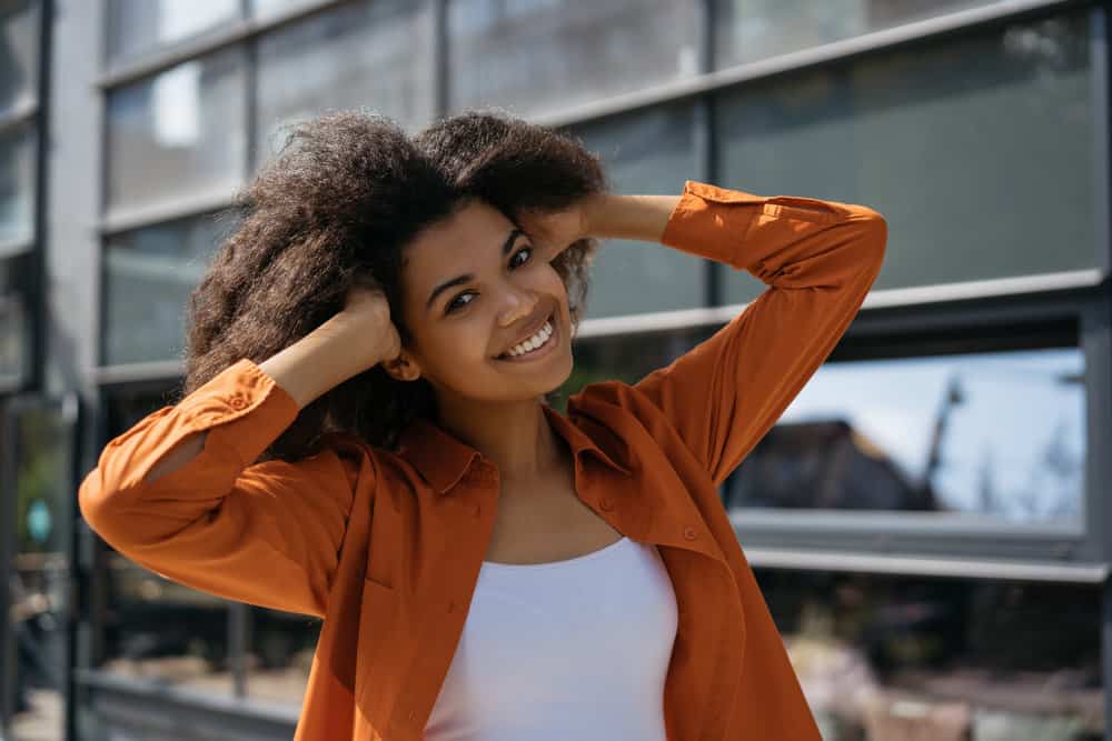 An African girl is wearing clothing made from synthetic fibers and breathable fabric to retain her hair's natural oils.