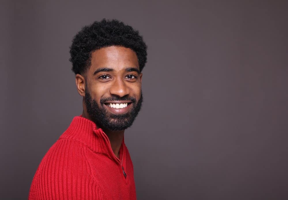 A young man boasts facial hair growth after adhering to an exercise routine that supports hair follicle health.