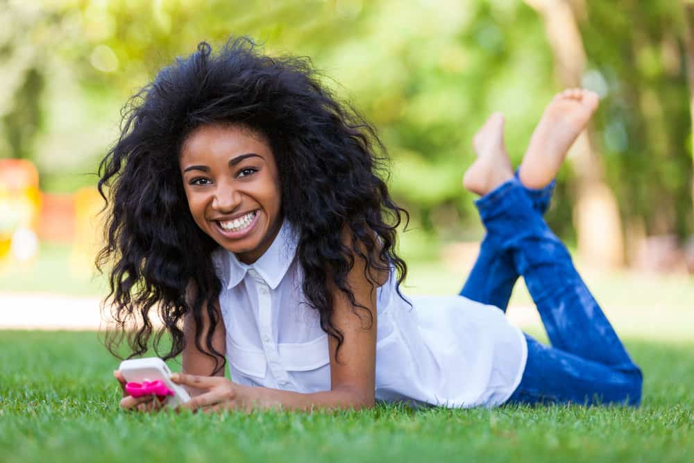 An African American female is researching cute hairstyles for black little girls on her new iPhone model.