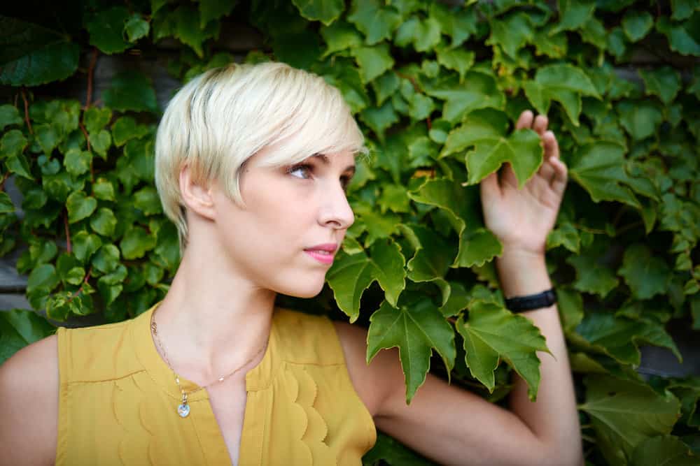 A white lady with a daring pixie cut style at an awkward phase as she tries to grow long hair, which is all the rage in her town.