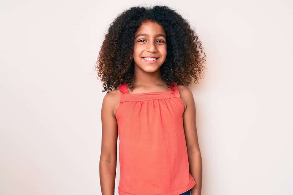 A cute little black princess with long hair wearing one of the most popular black girl hairstyles for curly thick hair.