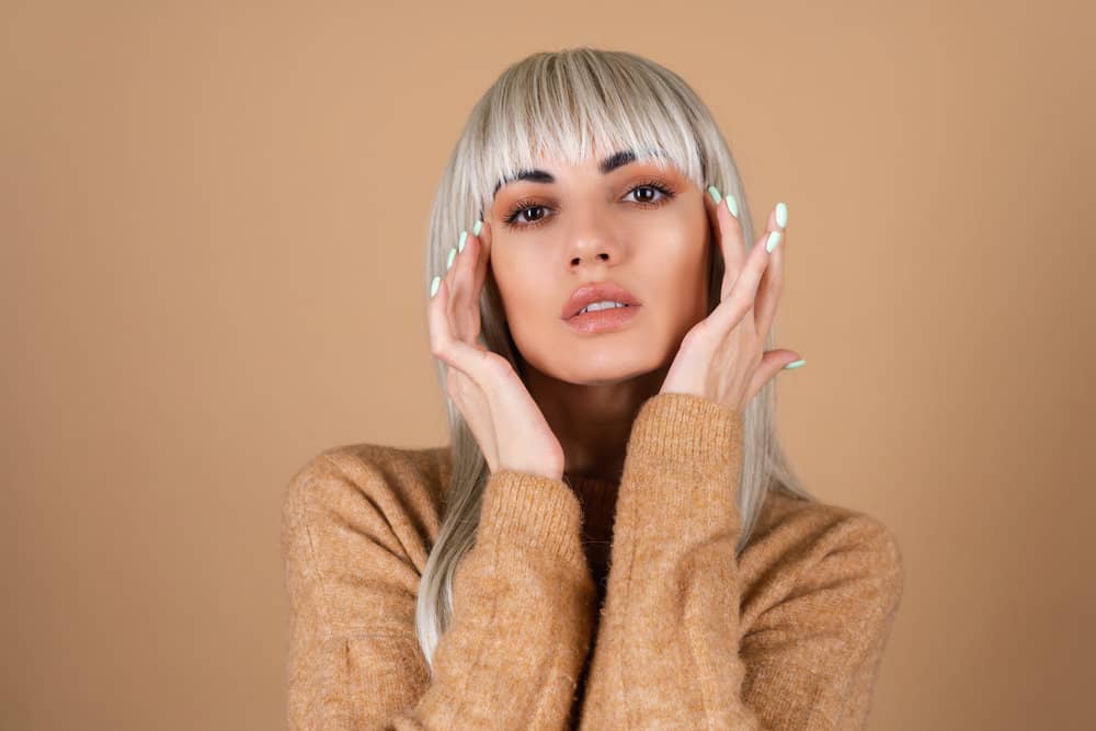 A blonde girl with bangs that are in an awkward stage as she's looking for ways to grow out bangs more quickly.