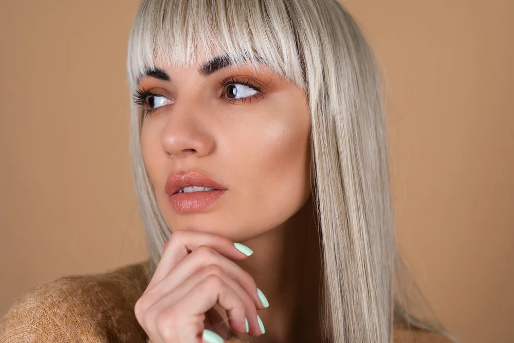 How Long Does It Take for Bangs to Grow Out Fully 3 A lady wearing natural-looking makeup with blunt bangs in an awkward stage caused by split ends and breakage.