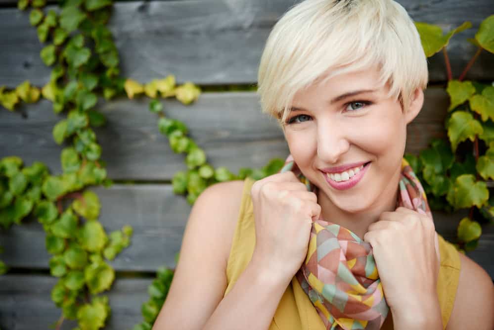 A Caucasian female with blonde hair follicles wearing her hair shorter after getting it styled in a pixie cut hairstyle.