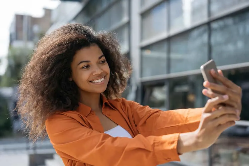 Satin vs. Silk for Hair: What Is Better for Your Hair? 7 African American female that's trying to settle the debate between silk or satin pillowcases by showing off her hair.