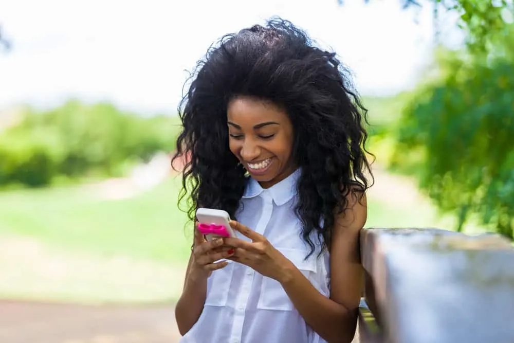 A young black girl using texting with other teenage black girls on her new mobile phone.