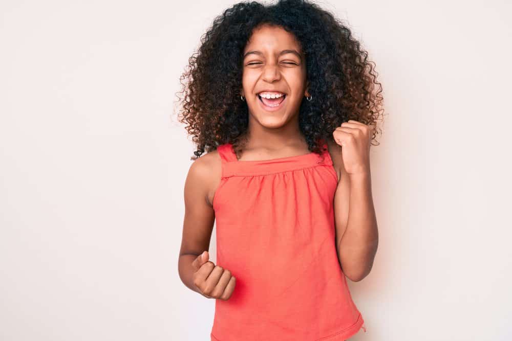 A cute young girl is wearing one of our favorite hairstyles for black kids with naturally curly African American hair types.