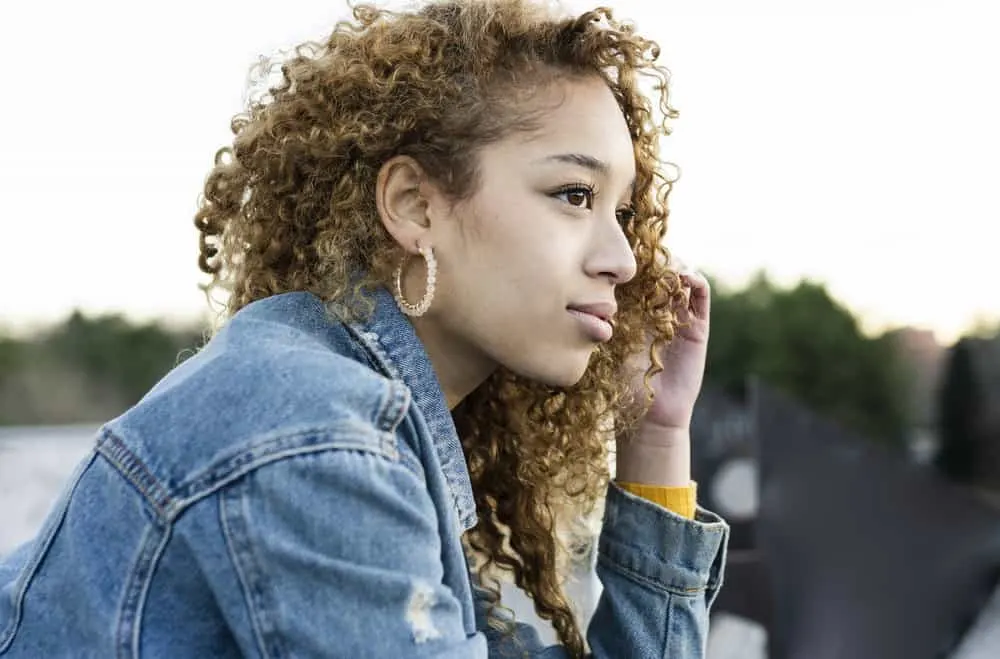 15 Cute Birthday Hairstyles for White and Black Girls 6 A pretty black lady with wavy hair has a stylish dark brown-blondish hair color as she poses for this picture.