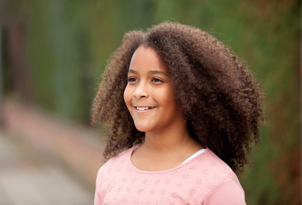 A beautiful young 12-year-old child with a beautiful hairstyle styled with a curl cream and human hair extensions.