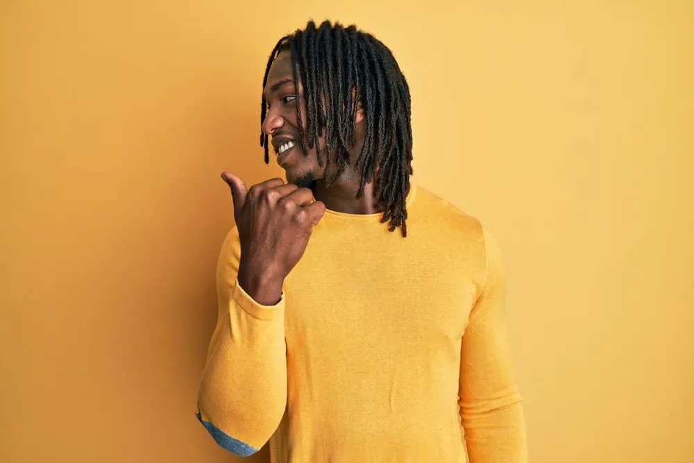 How to Get Freeform Dreads Fast: DIY Step-by-Step Guide 3 A black man with long freeform dreads is wearing a yellow form-fitting muscle shirt while looking behind him.