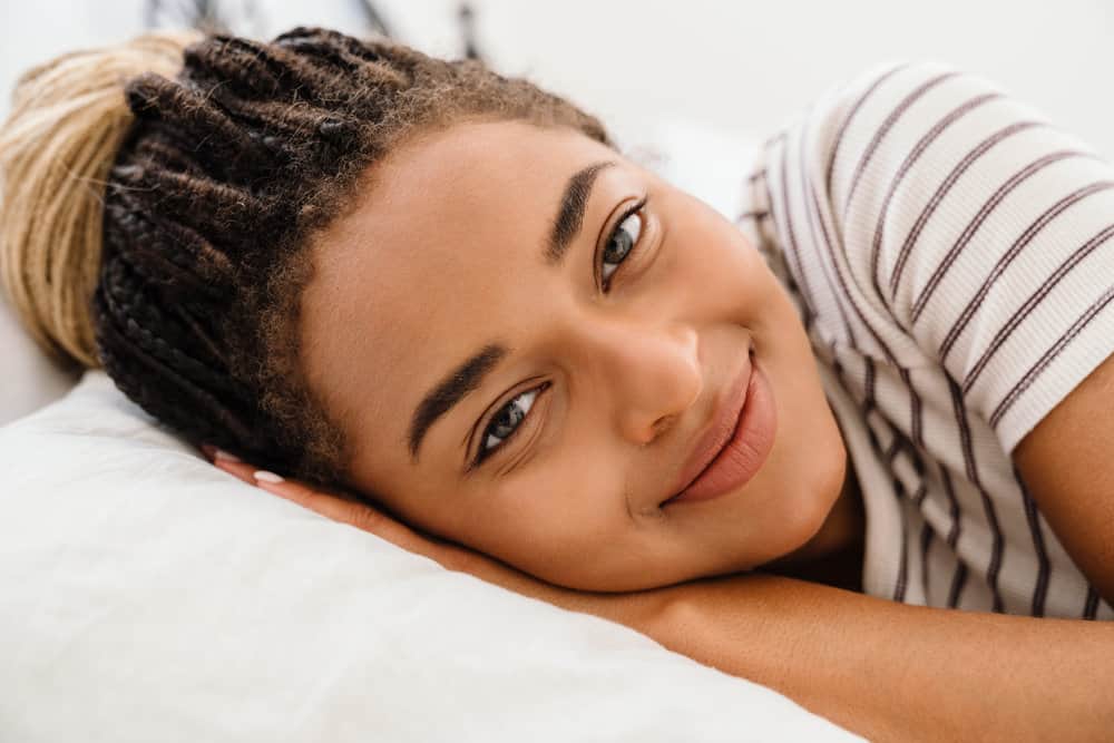 A young black woman with a type 4 hair type has braids with a defined grid pattern on an asymmetrical head shape.