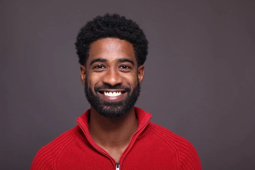A young African American man has a facial hair growth regimen that includes eating a healthy diet.