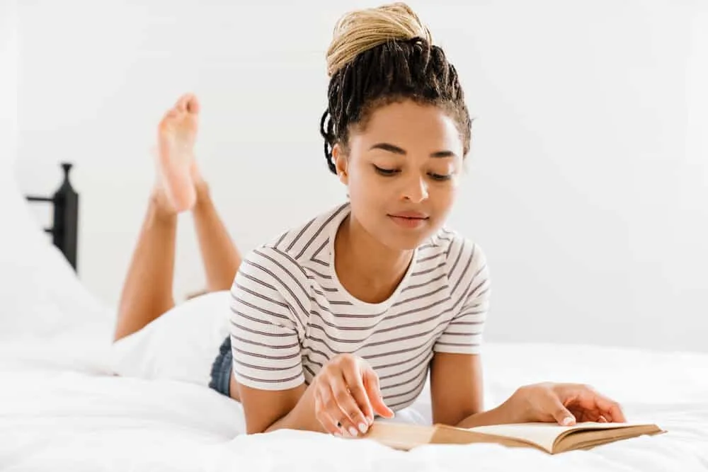 Microlocs vs. Sisterlocks: What's the Difference? Which is Better? 9 African female reading a book on how to install sisterlocks without formal training on her specific hair texture.