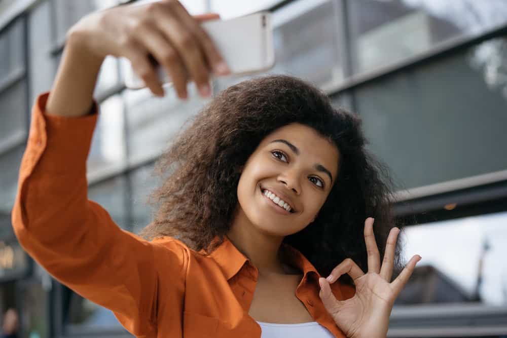 A beautiful light-skin black girl with curly hair styled with natural oils and sleeping on traditional bedding materials.