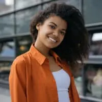 A cute black girl with a curly and textured hair texture that's moisturized after sleeping on a satin pillowcase.