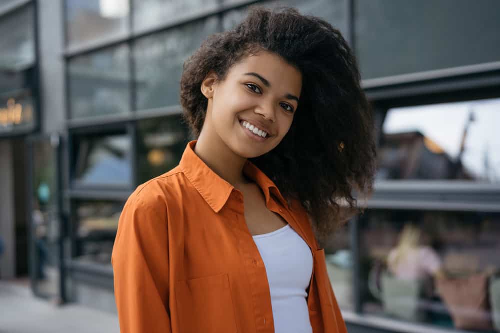 A cute black girl with a curly and textured hair texture that's moisturized after sleeping on a satin pillowcase.