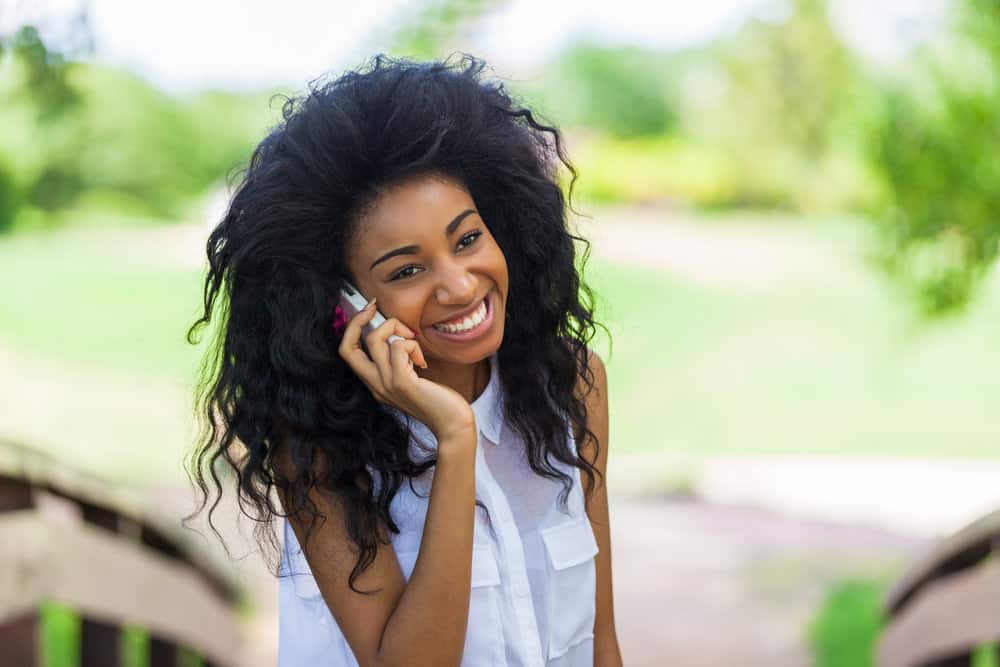 A young black girl with a medium hair length is allowing her curls to breathe after wearing the perfect protective style.