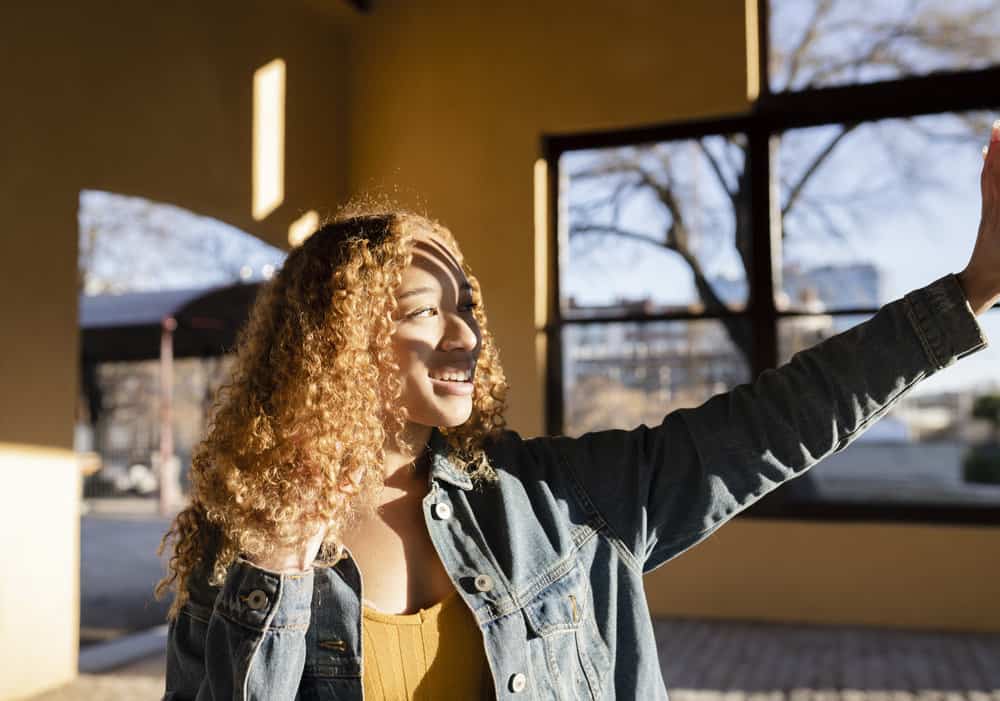 A birthday-ready lady with curly hair at sunset creates a dramatic look as she prepares for her next birthday party.