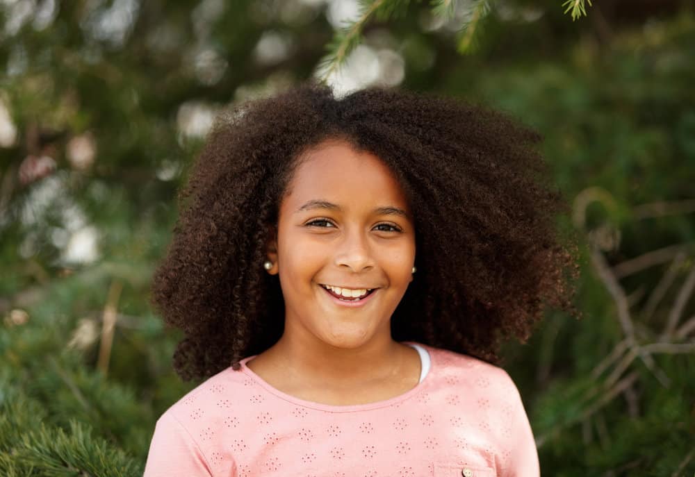 A young black female with long hair styled without any hair accessories (like a rubberband) or tools (like a flat iron).