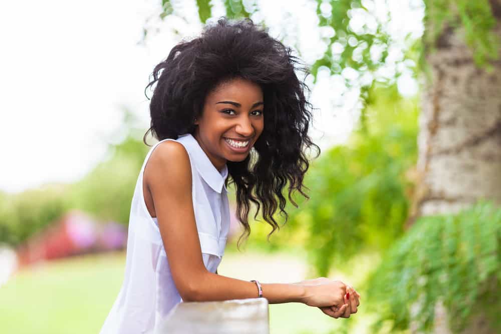 A cute teenage black girl with a great smile wearing a shoulder-length free-flowing style after removing a braided bun.