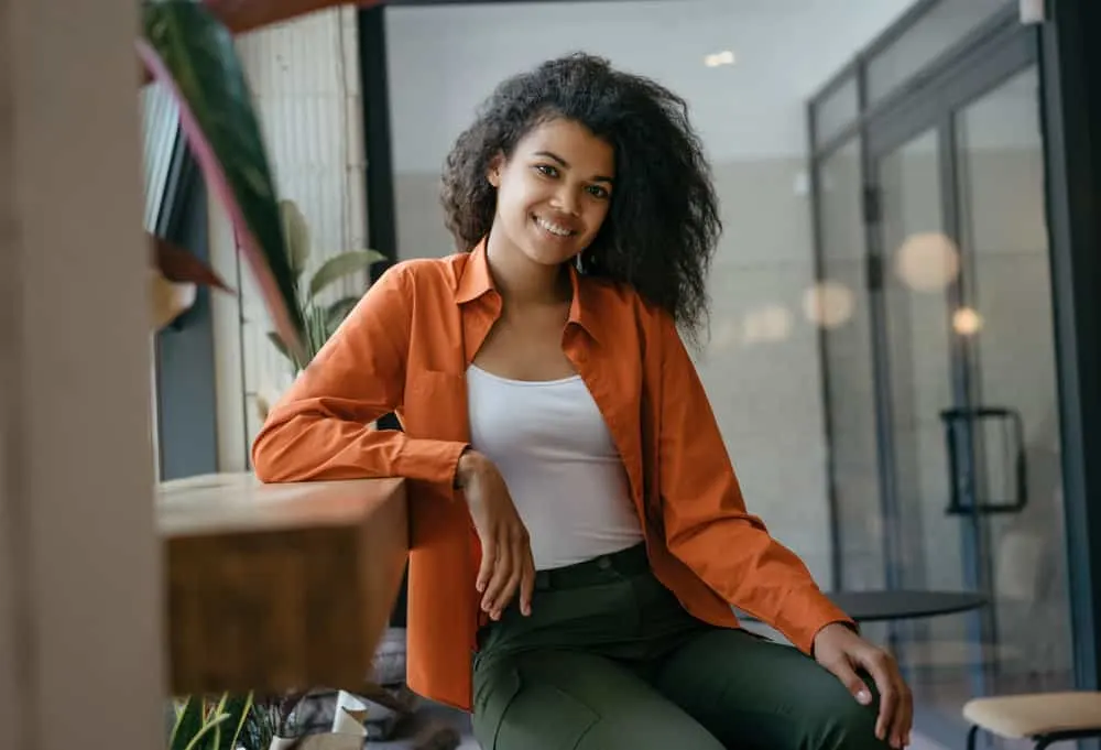 Satin vs. Silk for Hair: What Is Better for Your Hair? 4 A black woman with a cute smile is wearing a casual shirt made from mulberry silk fibers to protect her hair strands.