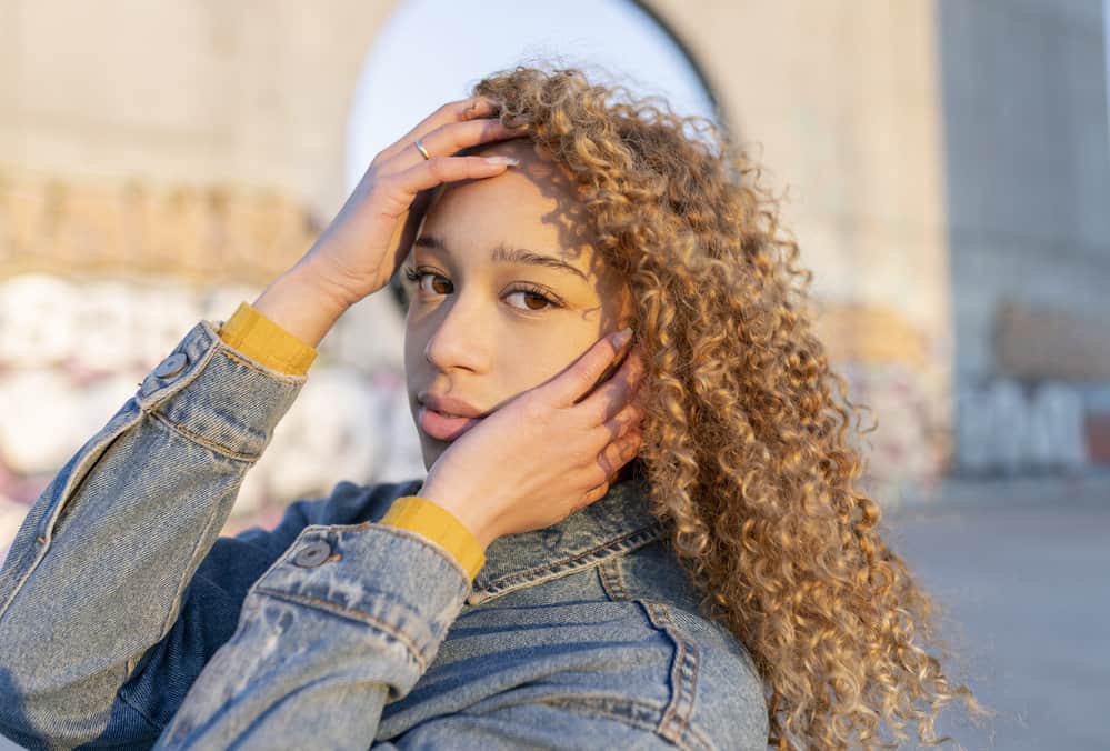 An absolutely gorgeous lady with curly long hair wearing a cute birthday hairstyle on blonde balayage hair.