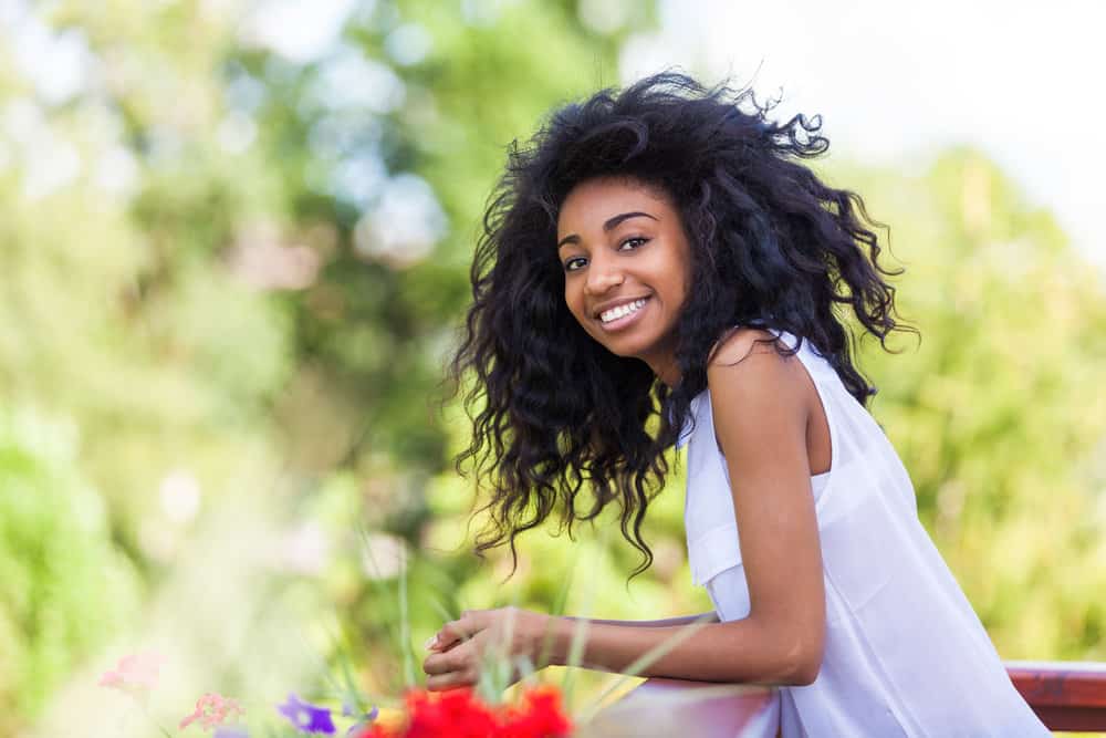 A black teenage girl with dark hair allowing it to hang free in a shoulder-length quick hairstyle creating a finished look.