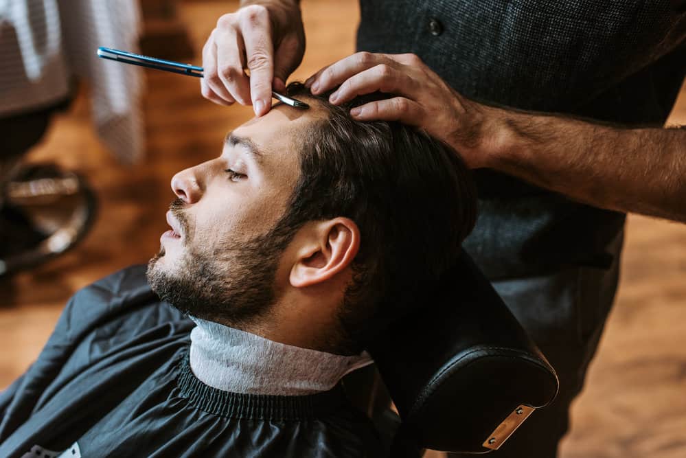 The white man's hair is being transformed into a sleek wavy Edgar haircut by his local barber at a WalMart salon.