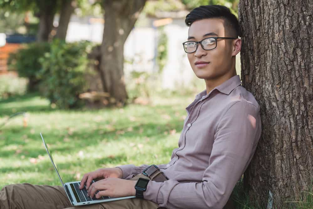 This Asian man is stylish with his dark brown hair styled in a parted two-block haircut and defined type 1 texture.