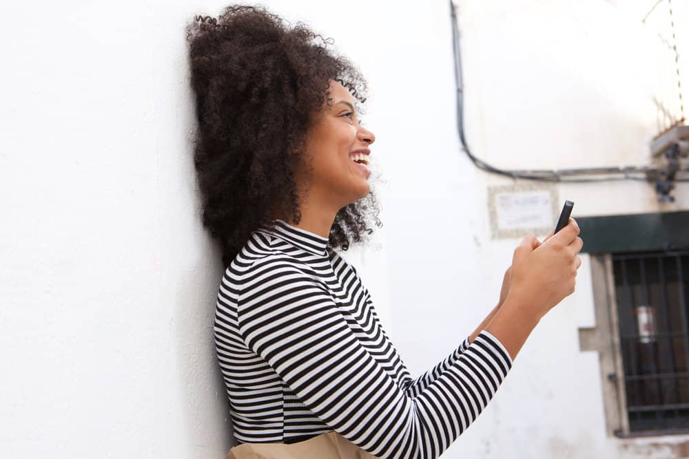 A light-skinned black girl from Newark, New Jersey, has uneven, wavy hair with split ends after neglecting her curls.