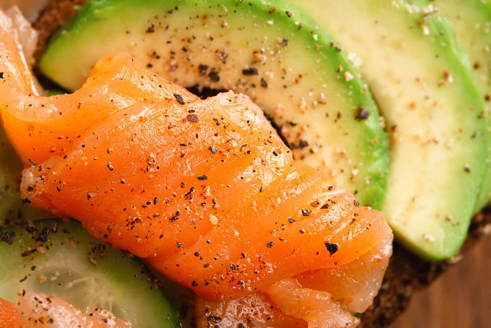 A tantalizing close-up of salted salmon layered on top of a creamy avocado on a slice of toasted bread.