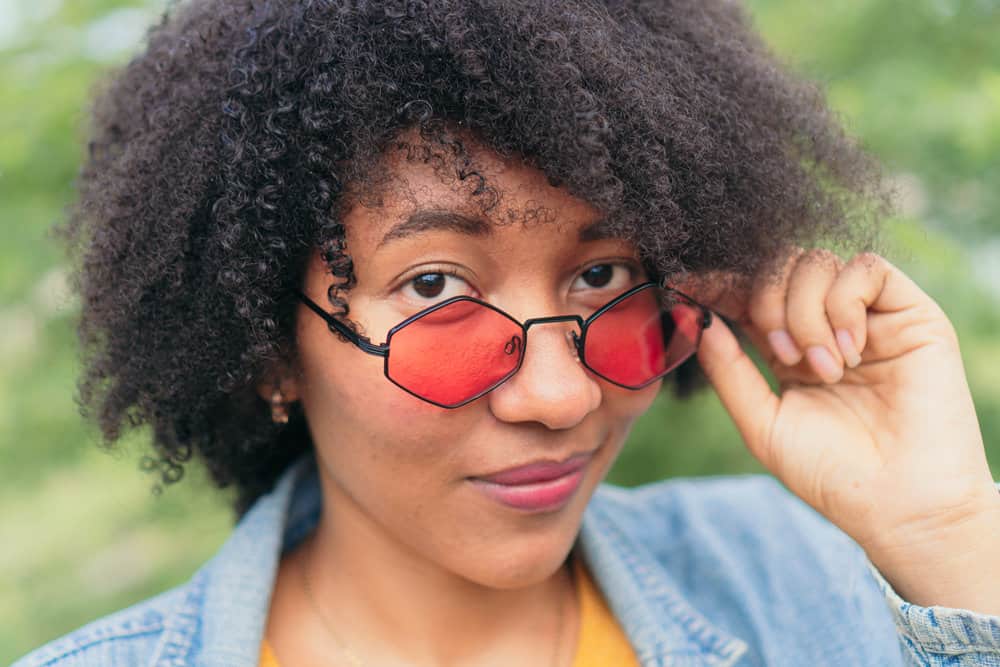 African American female with natural curls treated with bentonite clay hair mask to fix her dry hair cuticles.