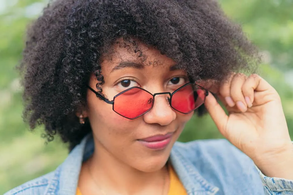 Aztec Clay Hair Mask: Benefits & How to Use It Step-By-Step 1 African American female with natural curls treated with bentonite clay hair mask to fix her dry hair cuticles.