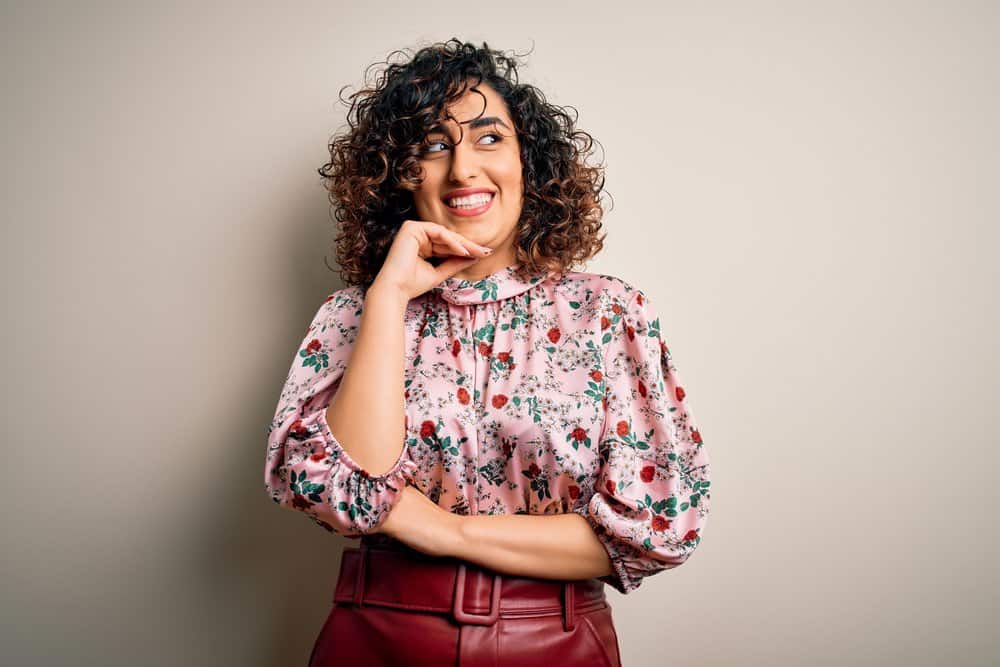 Face-framing highlights create a contrast with the burgundy shades in her shirt and the woman's beautiful skin color.