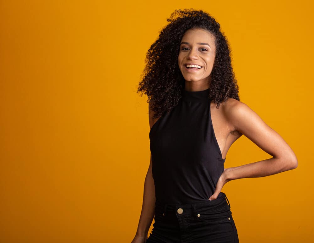 A captivating black girl with medium hair length is wearing a fun medium messy shag and casual jeans, and a black shirt.