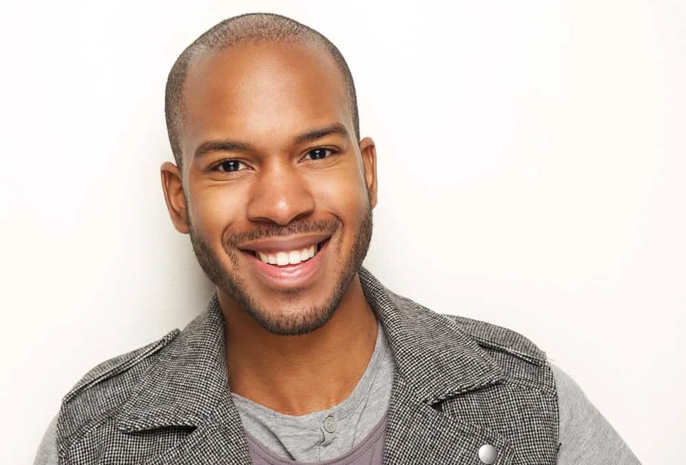 Best Male Haircuts for Receding Hairline and Widow’s Peak 19 A stylish and bold African American man with a mid-bald fade has short hair after getting a buzz cut.