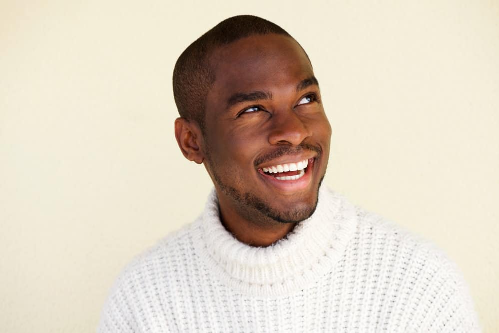 A handsome African male with a military fade haircut (e.g., regulation cut) has very short hair preparing for boot camp.