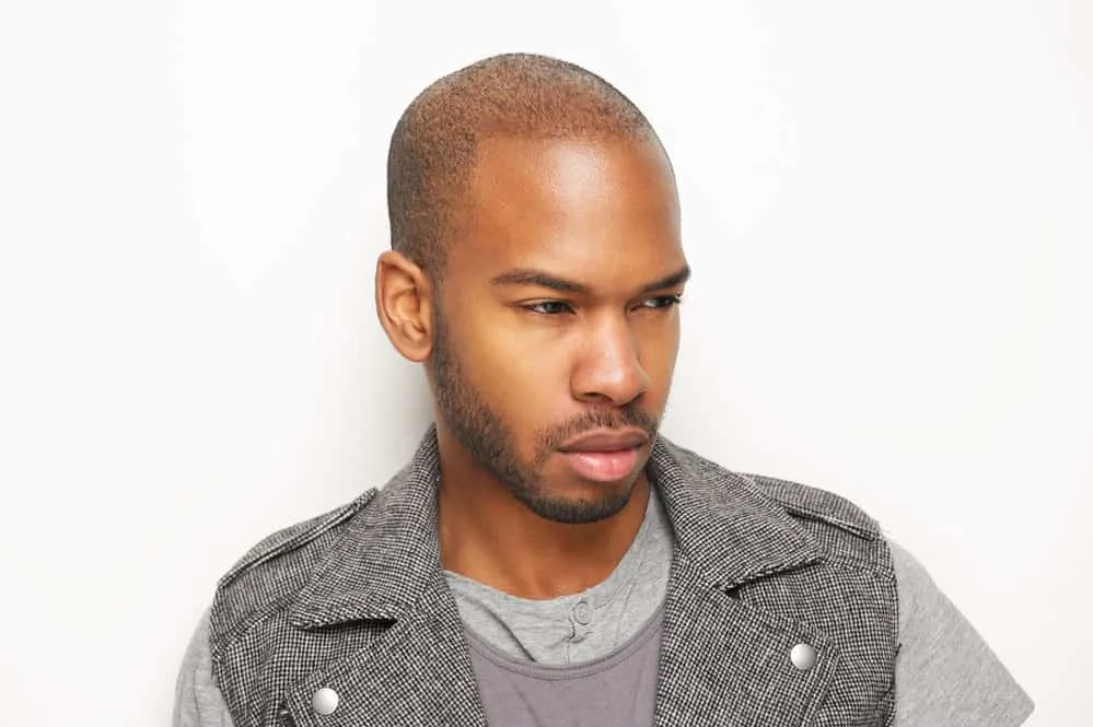A black man with a crew cut has been exploring receding hairline haircuts that work with his hair's natural texture.