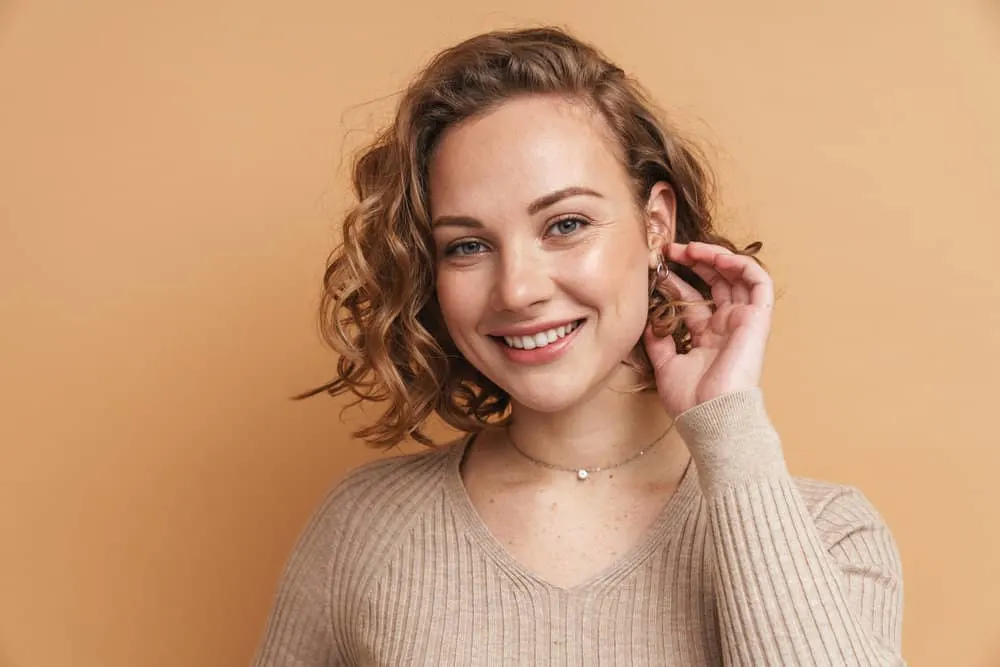 12 Best Medium-Length Haircuts With Layers, Bangs, & More 4 A young woman with shoulder-length layered hair was styled with stunning layers that flowed effortlessly.
