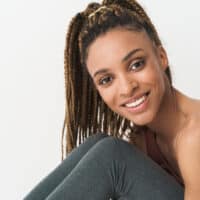A cute African female wearing long crochet braids covering her own hair strands with a protective hairstyle.