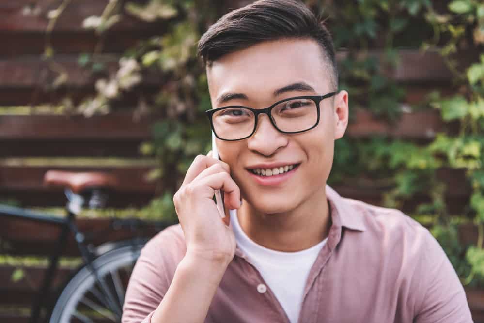 An Asian male with a dark brown hair color is wearing a parted two-block haircut with a type 1 defined hair texture.