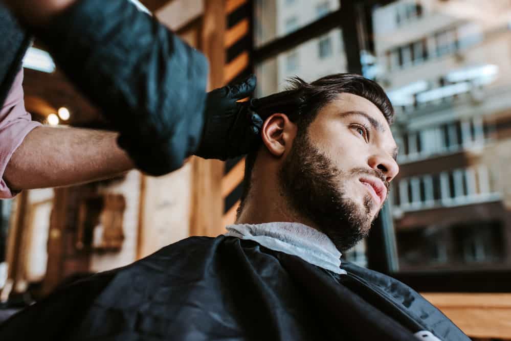 A white male with choppy hair is getting a mid-fade Edgar haircut resembling the baseball player Edgar Martinez.