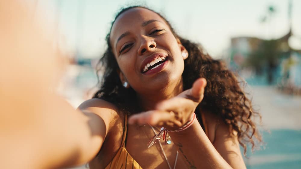 A dark-skinned black woman with naturally kinky curls that she has straightened with a flat iron.