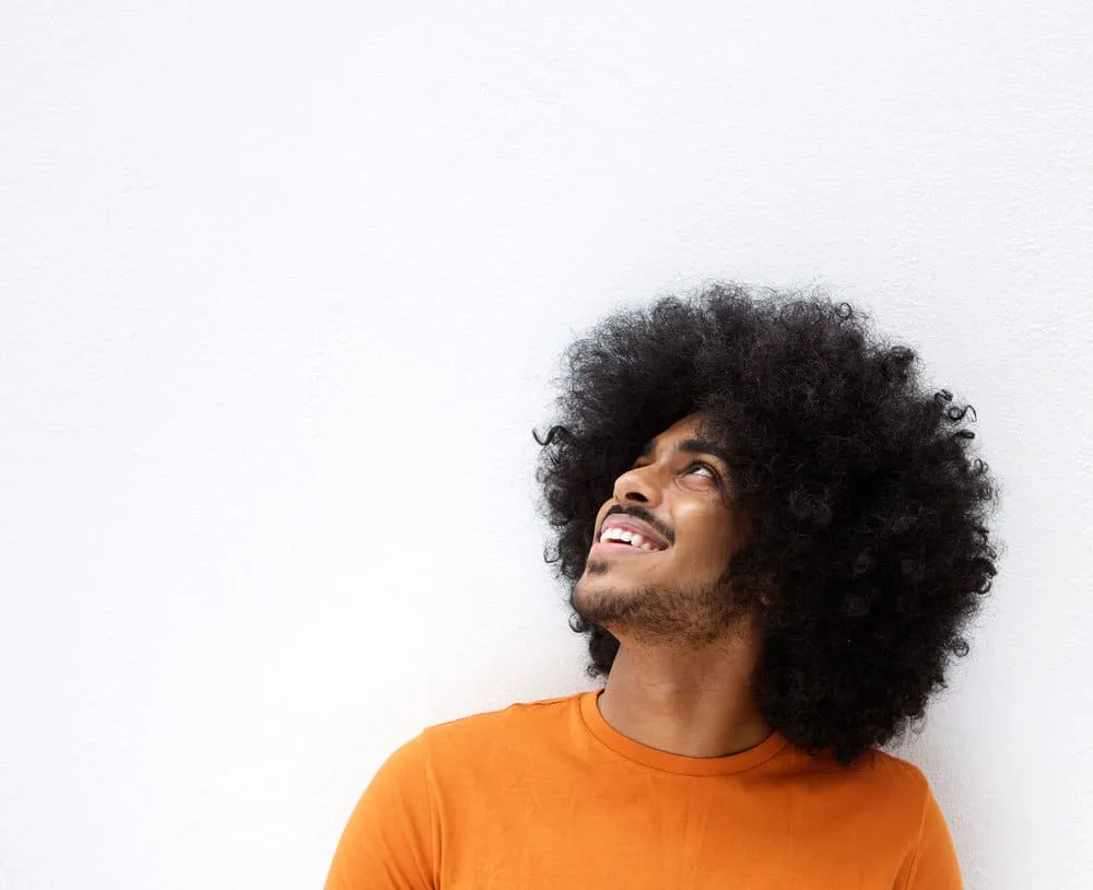 How to Make Your Hair Grow Faster and Thicker as a Black Man 5 A smiling black man with afro hair grows quickly due to using a hair regimen designed specifically for black men's hair.